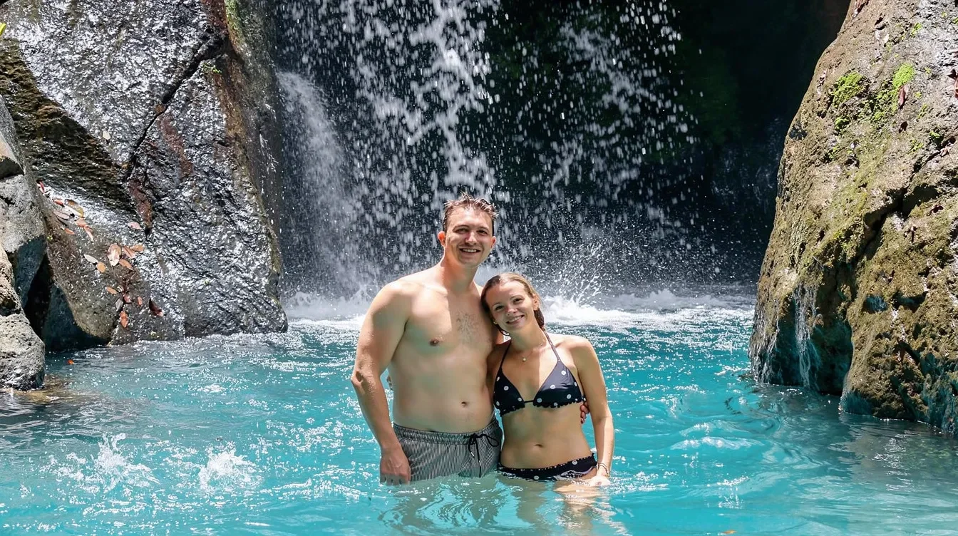 Pareja en agua azul bajo una catarata en Costa Rica
